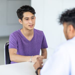 Kid in a purple shirt sitting at a desk talking to a doctor