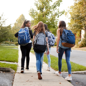 Three teens walking to school with backpacks on